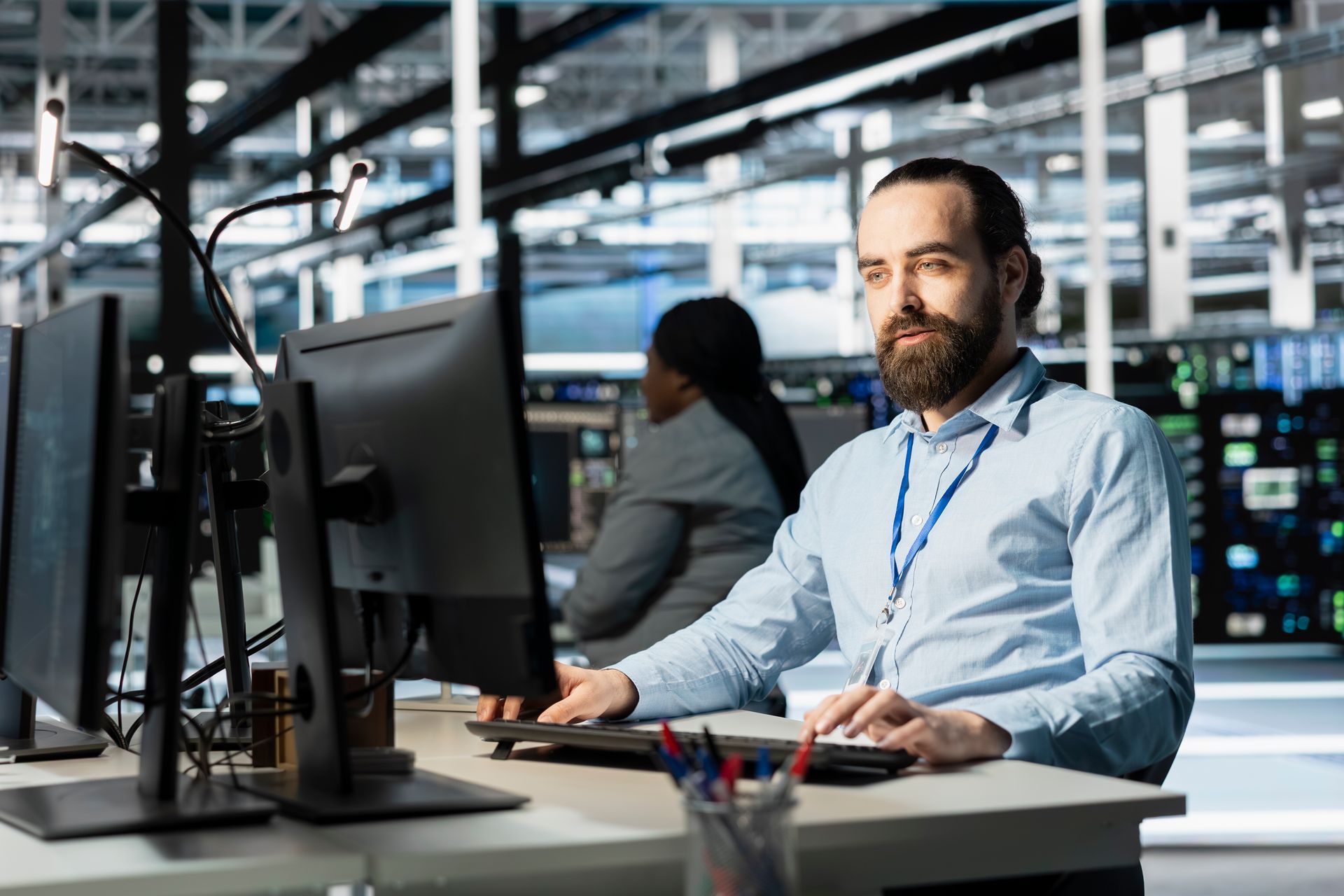 Man with a beard working at a computer in a data center.