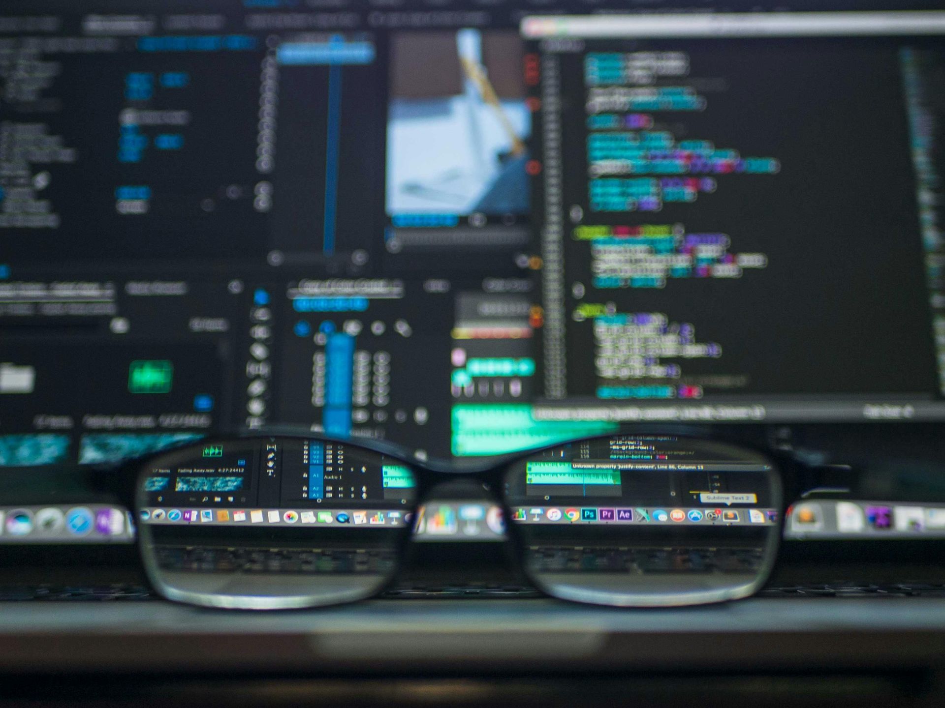 Glasses reflecting a computer screen with code. Dark background, focus on the glasses and code.